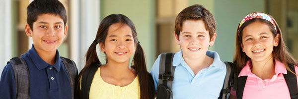 Four grade school kids happily standing