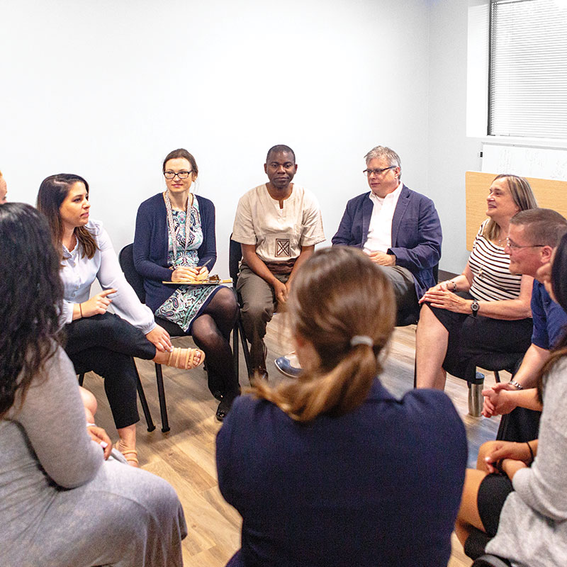 Sitting in a circle, a group of people participate in group therapy.